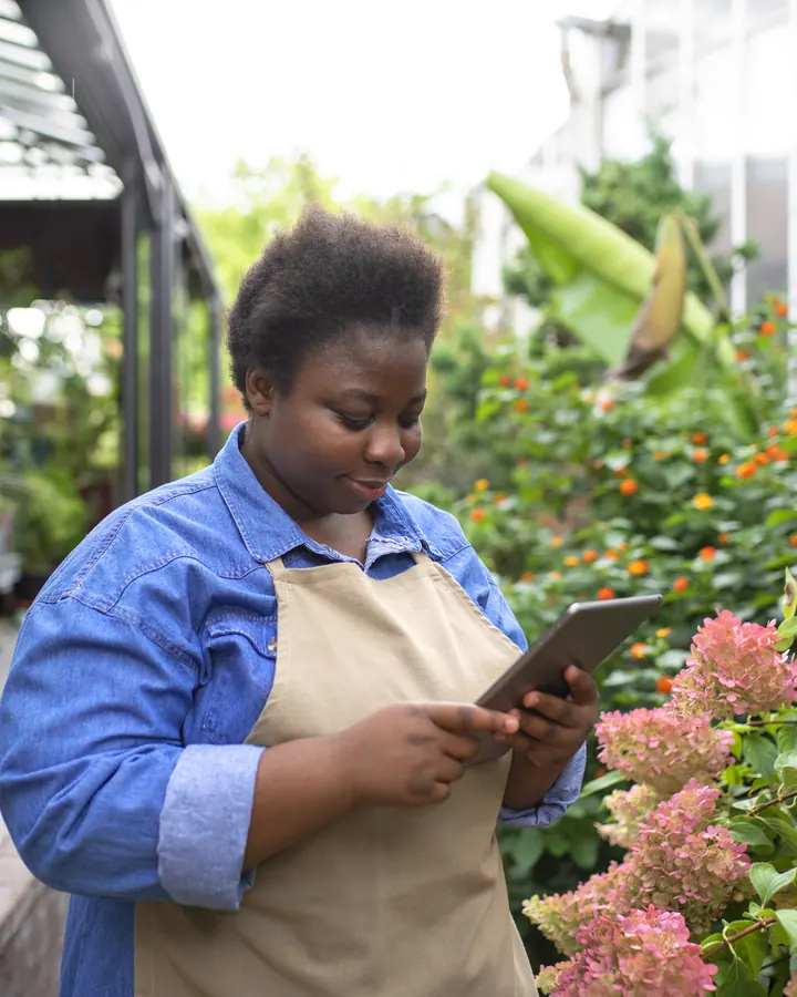 A florist checking her tablet outside her flower shop